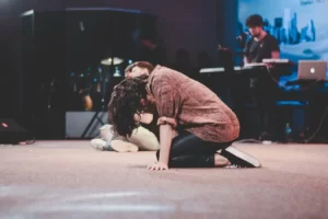 Jovem de joelhos em cima do palco. (Foto: Luis Alberto Sánchez Terrones / Unsplash)